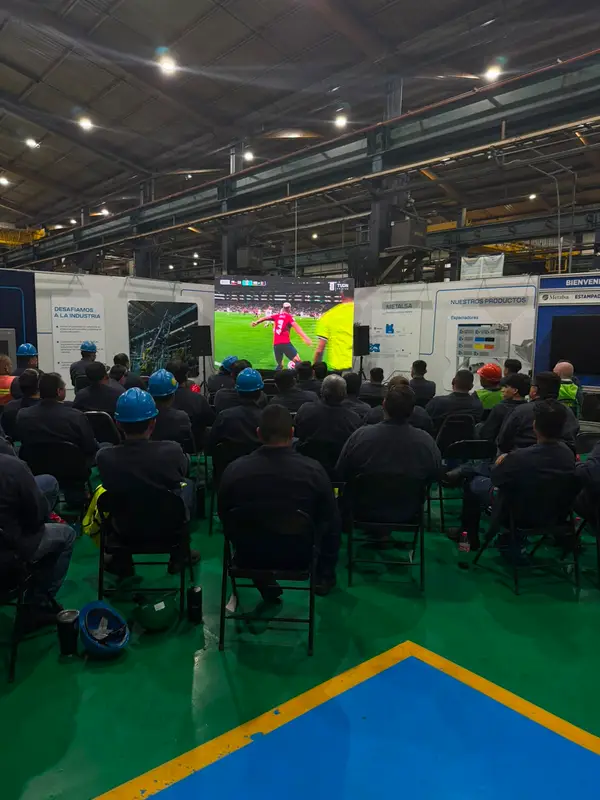 Trabajadores de una fábrica viendo un partido en una pantalla LED rentada