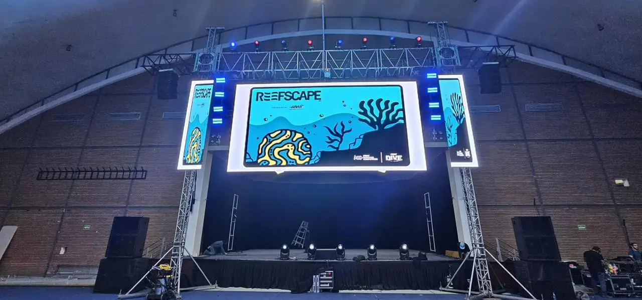 Escenario de una competencia con pantalla LED principal y dos pantallas laterales