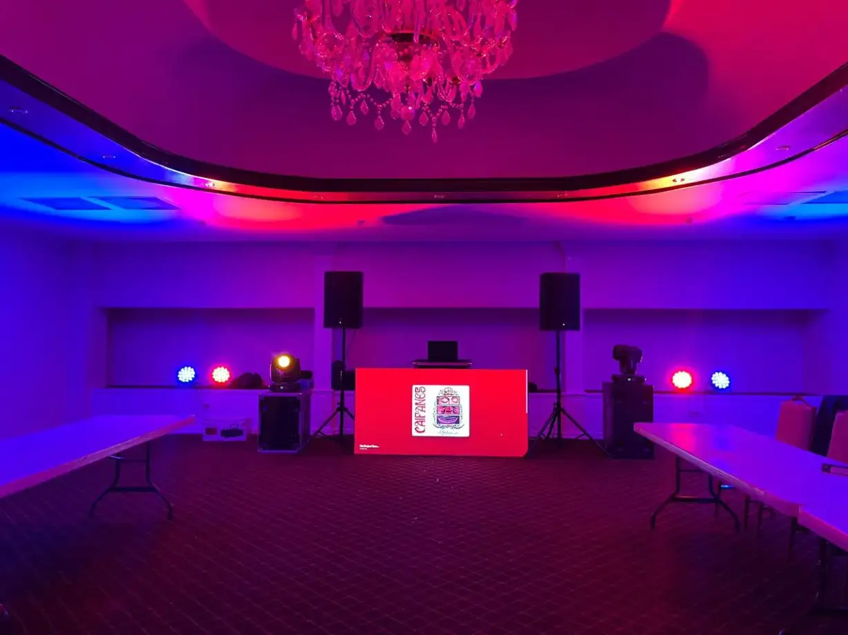 Booth de DJ con bocinas e iluminación en un salón de eventos