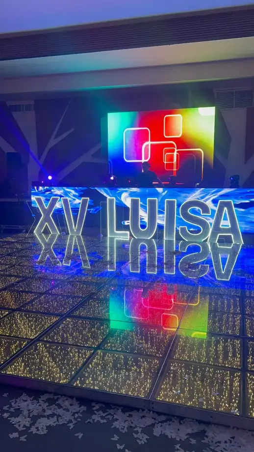 Letras gigantes iluminadas sobre piso LED en unos XV años