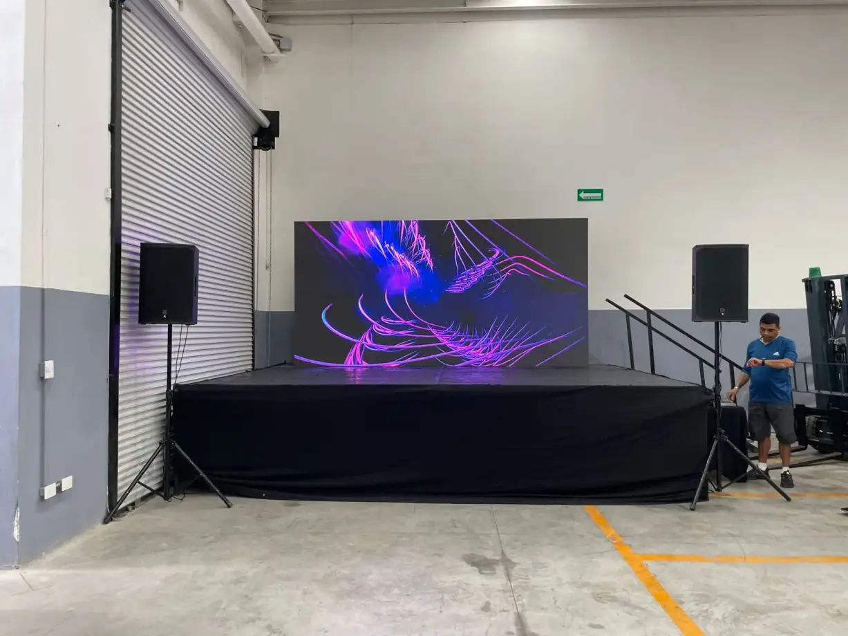 Pantalla LED de 4x2 con bocinas a los lados sobre tarima
